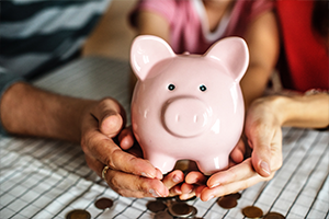 Family holding piggy bank with scattered coins on table