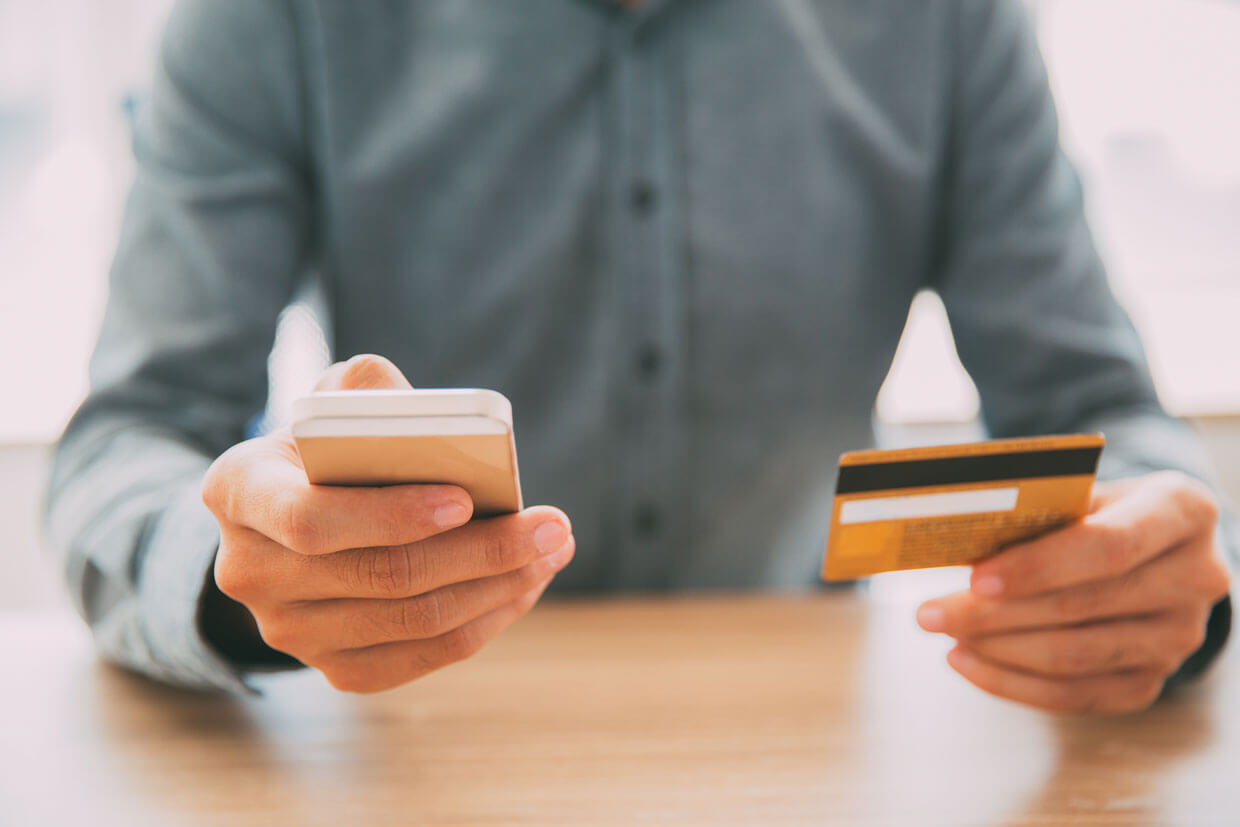 Businessman typing card data on mobile phone